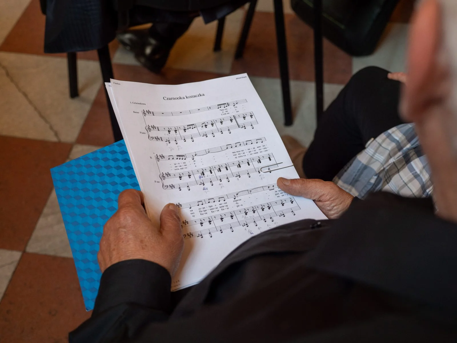 dwie ręce trzymające zapis nutowy piosenki pod tytułem Czarnooka kozaczka